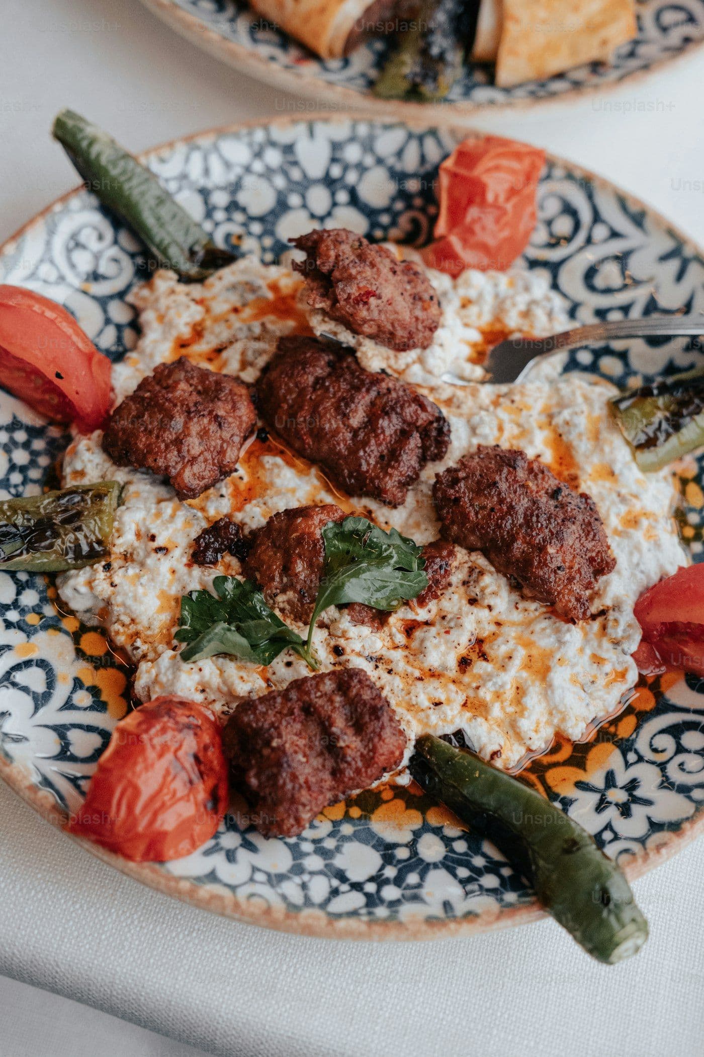 Lamb kofta with roasted vegetables on a patterned plate